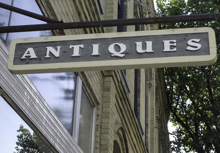 Simple sign hanging outside old brick building with antiques shop